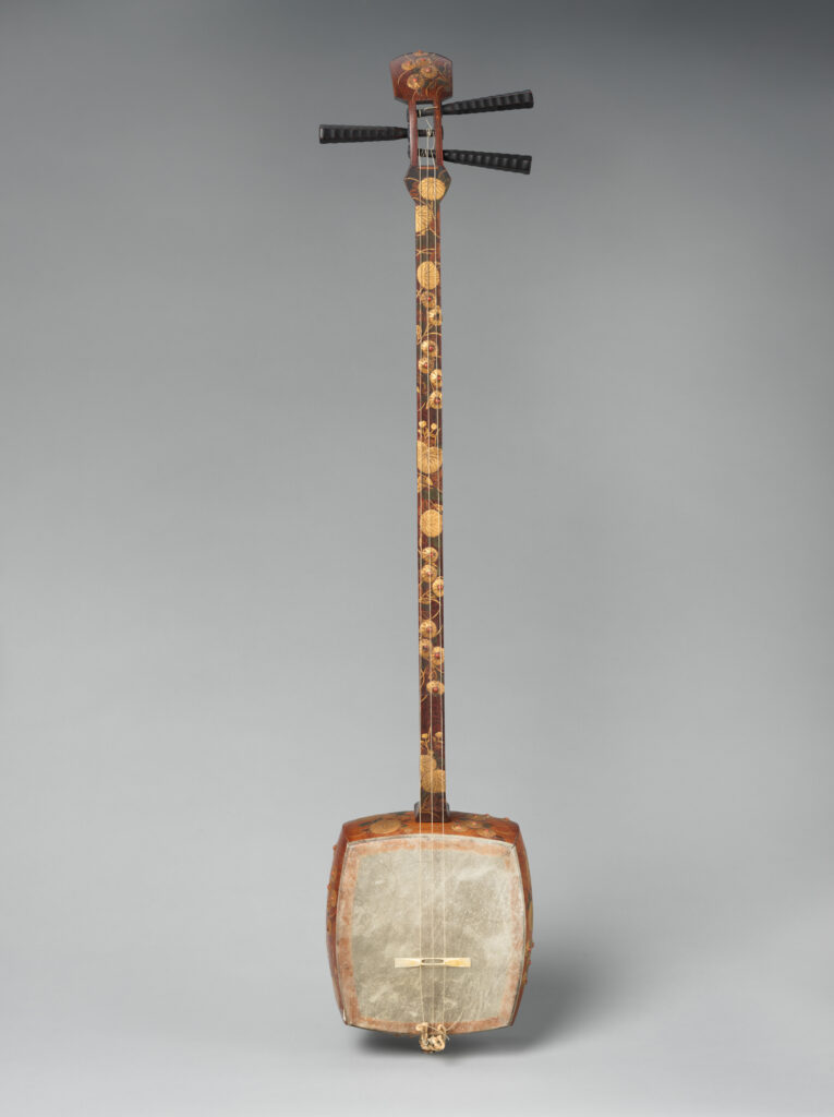 A three-stringed shamisen, ornately decorated. "Fretless banjo" doesn't come close to doing it justice.